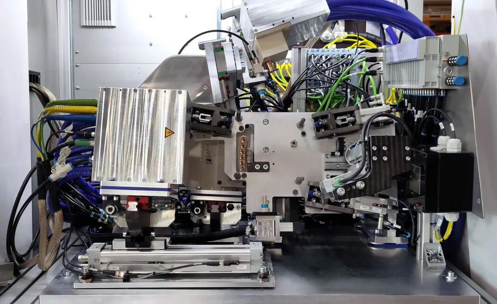 Automatic contacting with cooling connections, AC double contacting, and DC spring contacts in the e-mobility test bench Detailed view of the automatic contacting of an e-mobility inverter with automatic adjustment of the cooling connections, AC phase contacting on both sides, and a compact DC spring contact solution for reliable test sequences.